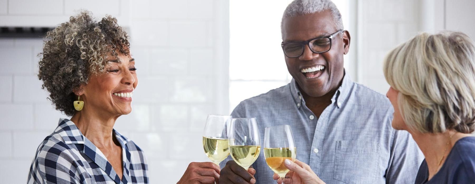 a few people smiling while holding wine
