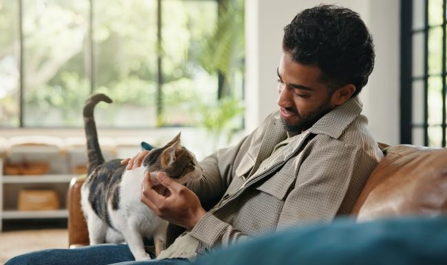 a man holding a cat while sitting on a couch