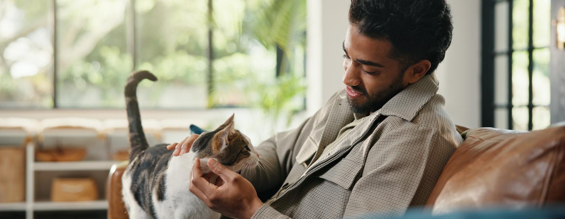a man holding a cat while sitting on a couch